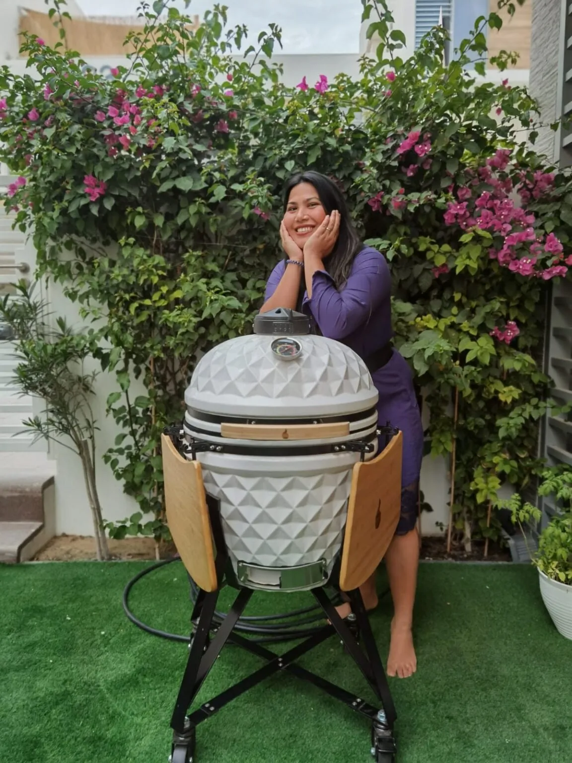 A woman leaning on a white diamond-pattern kamado under bougainvillea