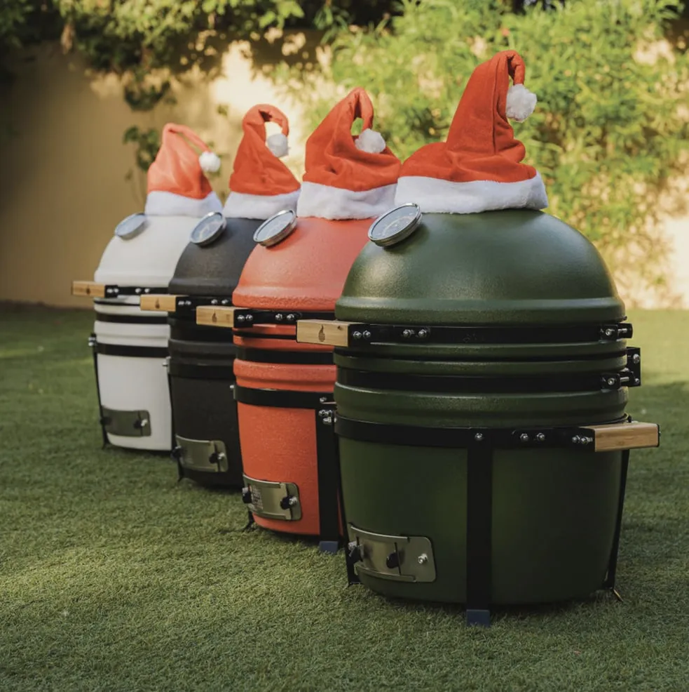 Four kamados lined up on a lawn, each wearing a Santa hat